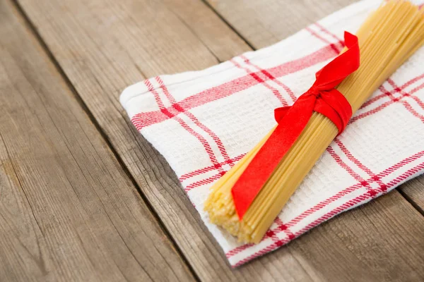 Paquete de espaguetis crudos atados con cinta roja — Foto de Stock