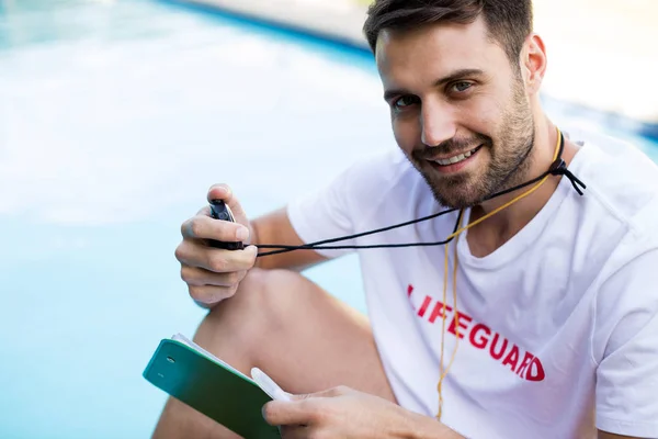 Портрет спасателя, держащего планшет и секундомер у бассейна — стоковое фото