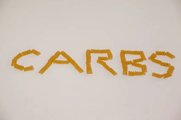 Conchiglie pasta arrange in shape of carbs text — Stock Photo, Image