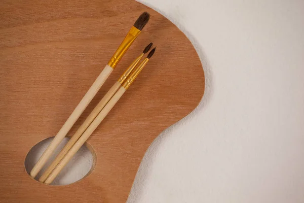 Wooden palette and paint brushes — Stock Photo, Image