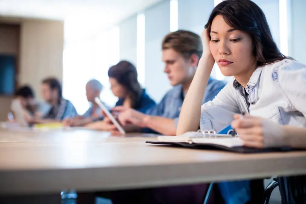 Mujer sentada en la sala de reuniones con sus colegas — Foto de Stock