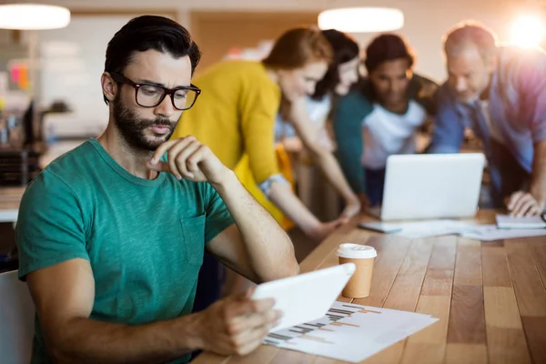 Mann nutzt digitales Tablet, während Team im Hintergrund arbeitet — Stockfoto