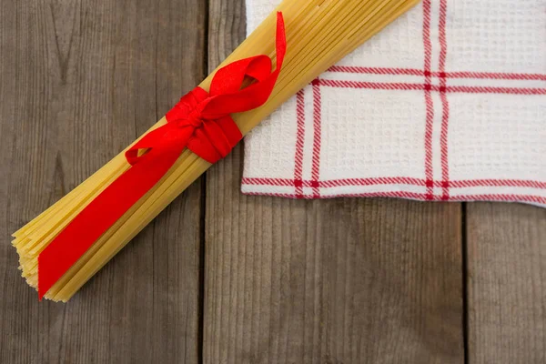 Paquete de espaguetis crudos atados con cinta roja — Foto de Stock