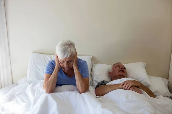 Senior woman getting disturbed with man snoring on bed — Stock Photo, Image