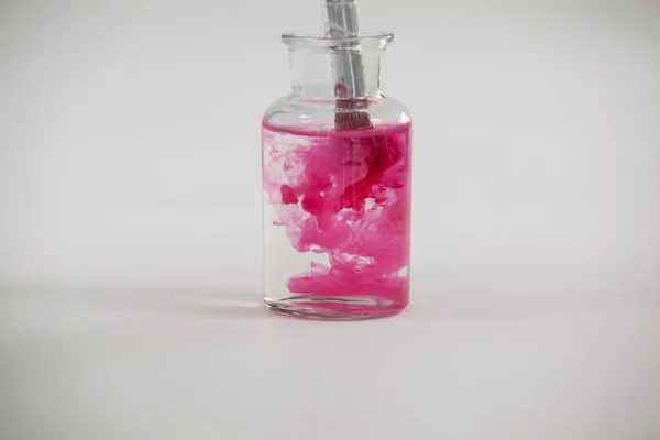 Pinsel mit rosa Farbe in ein mit Wasser gefülltes Glas getaucht — Stockfoto