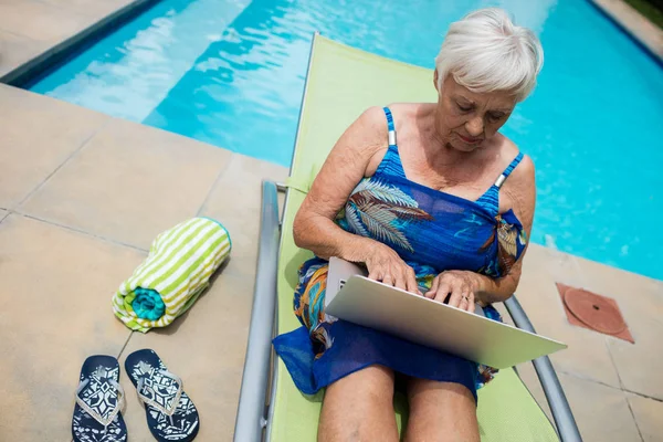 Senior kvinna använder laptop på solstol — Stockfoto