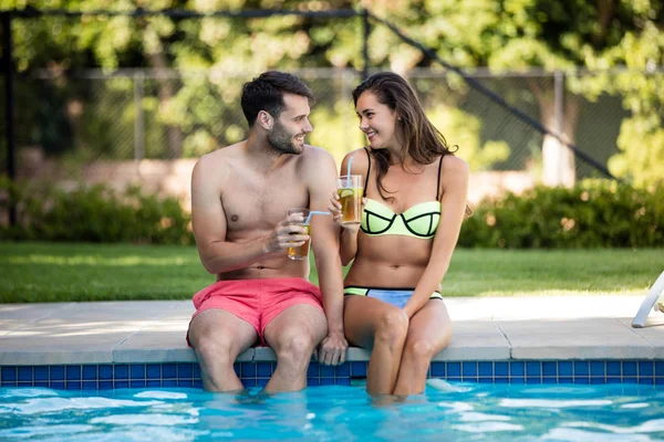 Jovem casal ter chá gelado na beira da piscina — Fotografia de Stock