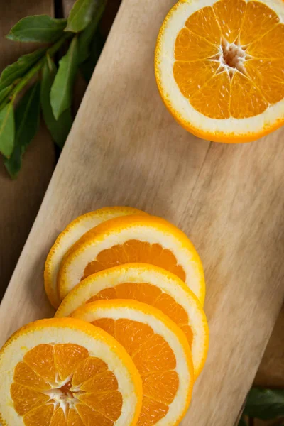 Ломтики и вдвое сокращенные апельсины на доске — стоковое фото