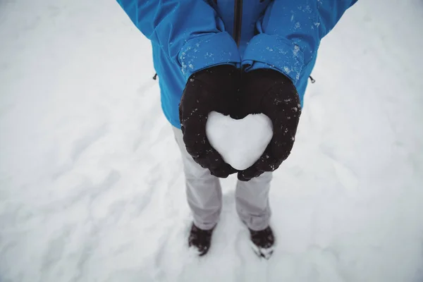Mannen i varma kläder håller snöiga hjärta — Stockfoto