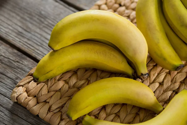 Plátanos mantenidos en mantel sobre mesa de madera —  Fotos de Stock