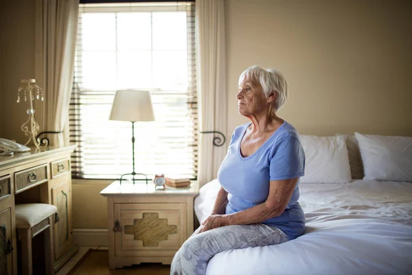 Bezorgd senior vrouw zittend op bed in de slaapkamer — Stockfoto