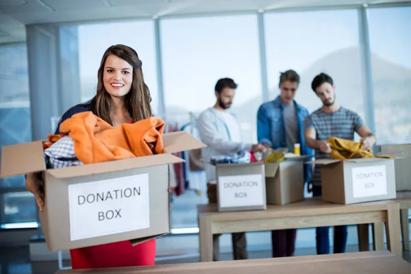 Donna sorridente in possesso di una scatola di donazione in ufficio — Foto Stock