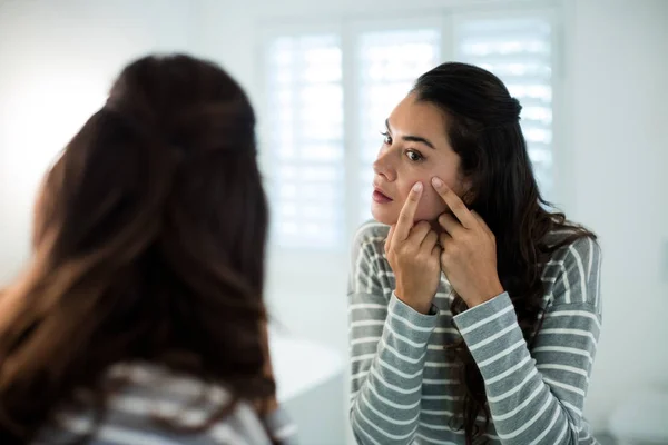 Vrouw knijpen puistjes voor badkamerspiegel — Stockfoto