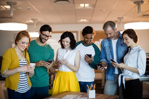 Team creativo di business sorridente utilizzando il telefono cellulare — Foto Stock