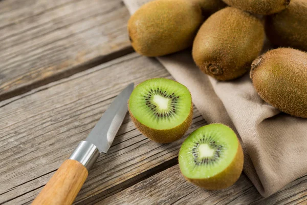 Kiwis with knife on wooden table — Stock Photo, Image