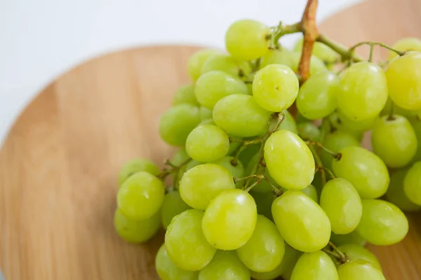Close-up de cachos verdes de uvas na tábua de corte — Fotografia de Stock