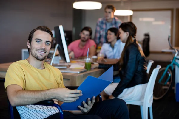 Körperbehinderter Mann im Rollstuhl mit Akte im Büro — Stockfoto