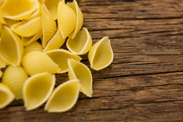 Conchiglie pasta on wooden surface — Stock Photo, Image