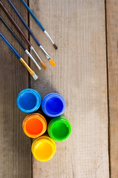 Paintbrushes and watercolors arranged on wooden surface — Stock Photo, Image