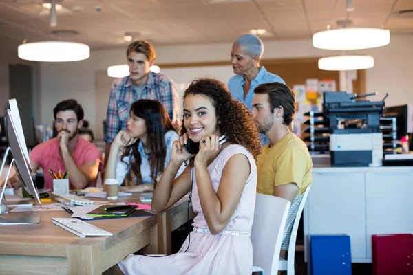 Frau mit Kopfhörern arbeitet mit ihrem Team im Büro — Stockfoto