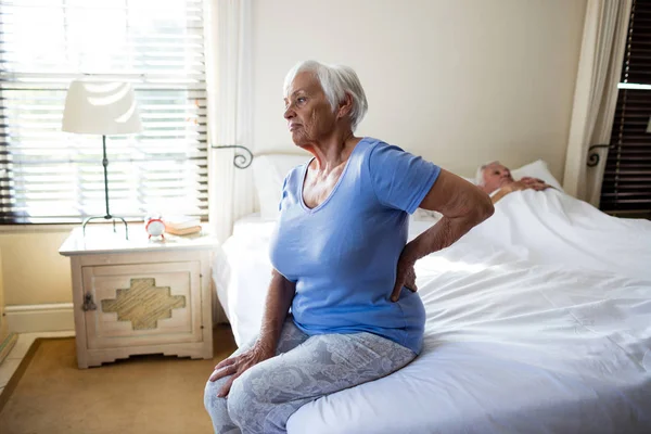 Senior vrouw lijden aan rugpijn in de slaapkamer — Stockfoto