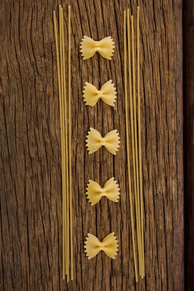 Farfalle i spaghetti na powierzchni drewnianych — Zdjęcie stockowe