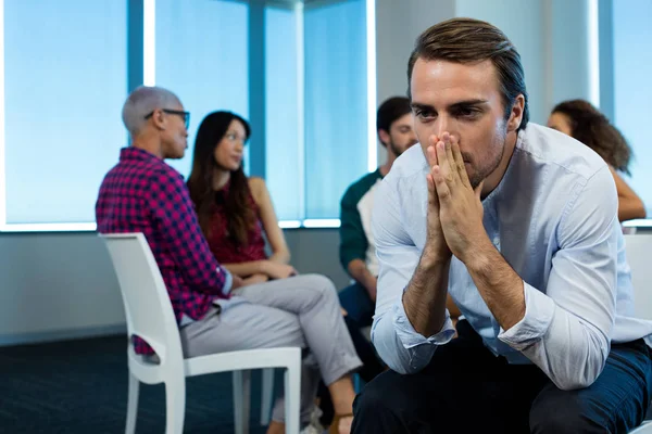 Mann weint, während kreatives Geschäftsteam im Hintergrund arbeitet — Stockfoto