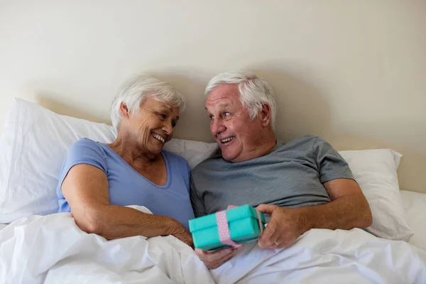 Uomo anziano che fa un regalo a sorpresa alla donna in camera da letto — Foto Stock