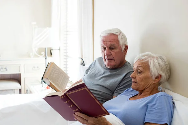 Pareja mayor leyendo libros en el dormitorio — Foto de Stock