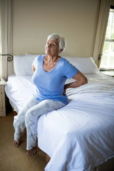 Старшая женщина страдает от болей в спине в спальне — стоковое фото