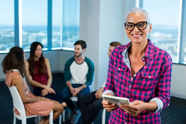 Woman using digital tablet while creative business team in background — Stock Photo, Image