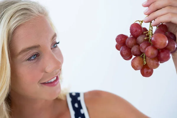 Mulher bonita olhando para um monte de uvas vermelhas — Fotografia de Stock