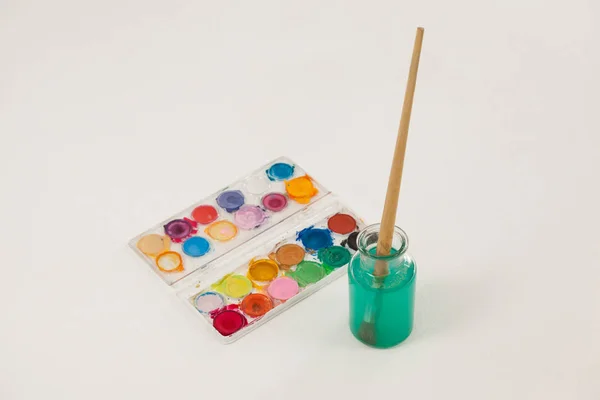 Paleta de acuarela y pincel con pintura azul sumergida en agua — Foto de Stock