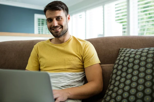 Portret van man met laptop in de woonkamer — Stockfoto