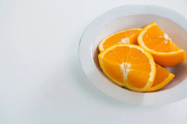 Fatias de laranjas em tigela no fundo branco — Fotografia de Stock