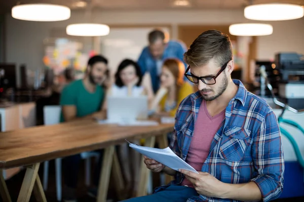 Hombre usando tableta digital mientras el equipo de trabajo en segundo plano —  Fotos de Stock