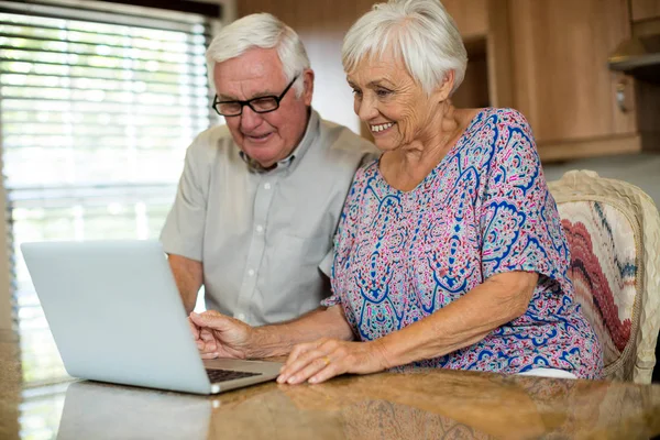 Senior couple using laptop in the kitchen — Stock Photo, Image