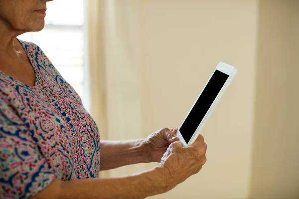 Senior vrouw met digitale tablet in woonkamer — Stockfoto