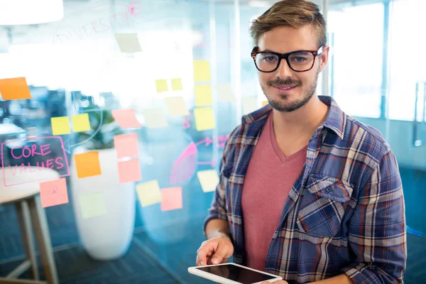 Man in office using digital tablet against sticky notes on wall — Stock Photo, Image