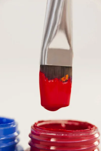 Paint brush dipped into red color against white background — Stock Photo, Image