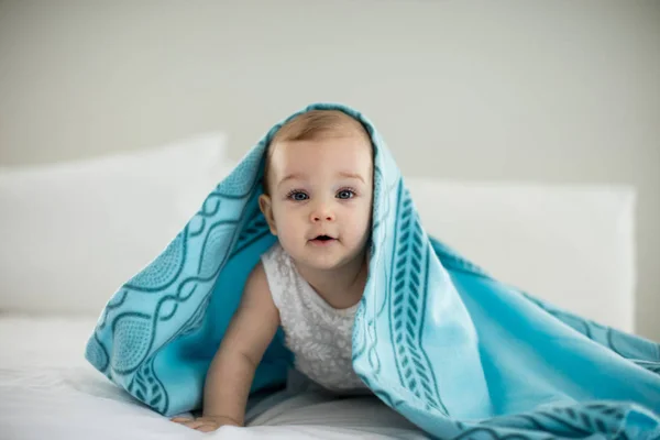 Schattige babymeisje onder de deken op bed — Stockfoto