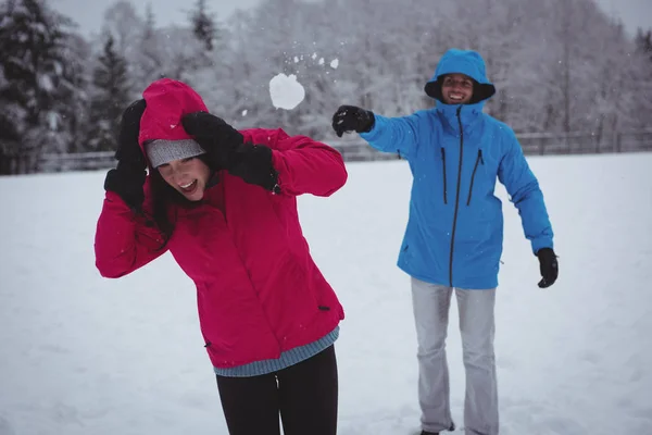 女性で雪玉を投げる男 — ストック写真