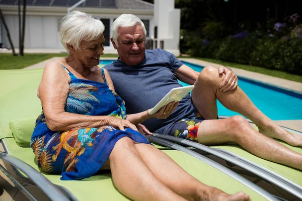 Senior couple looking at digital tablet on lounge chair — Stock Photo, Image