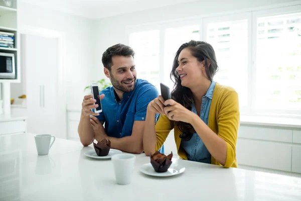 Пара с помощью мобильного телефона на кухне — стоковое фото