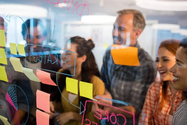 Equipo de negocios creativo mirando notas adhesivas en la ventana de vidrio —  Fotos de Stock