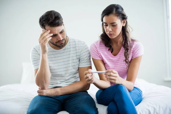 Besorgtes Paar erfährt Ergebnisse eines Schwangerschaftstests im Schlafzimmer — Stockfoto