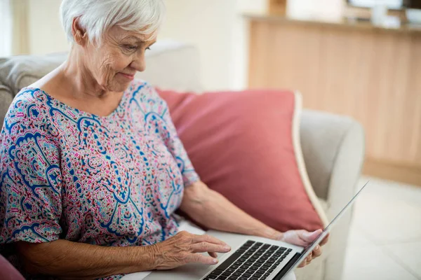 Mujer mayor usando portátil en la sala de estar — Foto de Stock