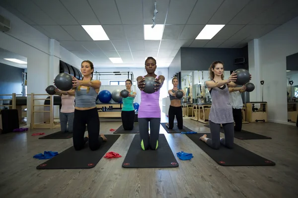 Fit women performing stretching exercise with fitness ball in gym — Stock Photo, Image