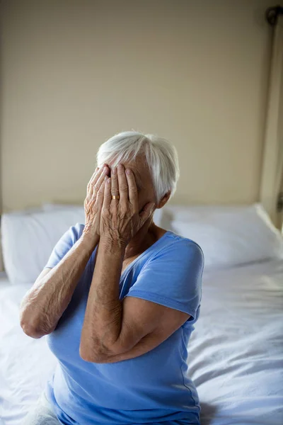 Benadrukt senior vrouw die betrekking hebben op haar gezicht met handen — Stockfoto