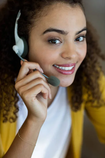 Sorridente dirigente del servizio clienti parlando in cuffia in ufficio — Foto Stock